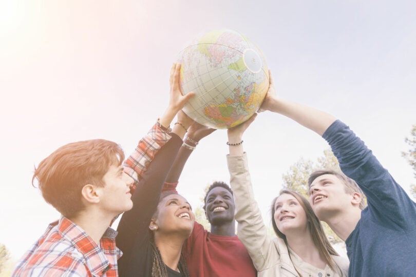 Grupo de jovens segurando o globo do mundo para cima.