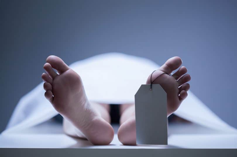 Foto próxima de pés de um corpo humano colocado em uma mesa de necrotério.