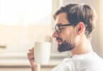 Homem sorrindo e segurando uma xícara de café.