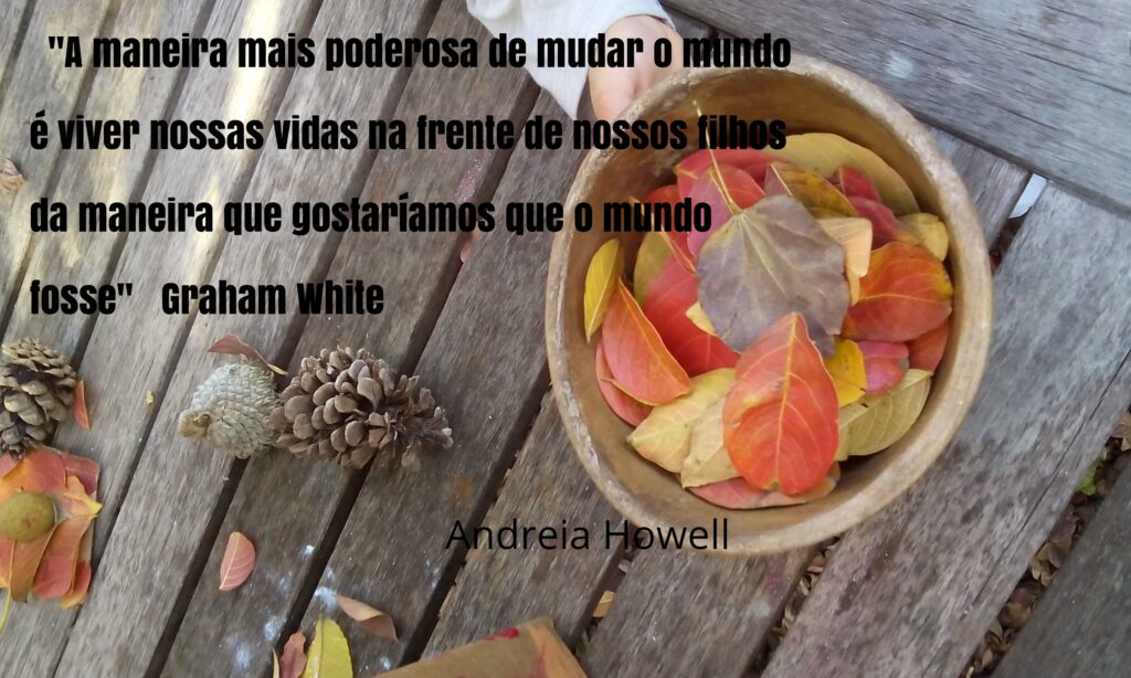 Imagem com a frase “A maneira mais poderosa de mudar o mundo e viver nossas vidas na frente dos nossos filhos da maneira que gostaríamos que o mundo fosse” . Ao fundo é possível ver a mão de uma pessoa segurando uma tigela de madeira com folhas coloridas.