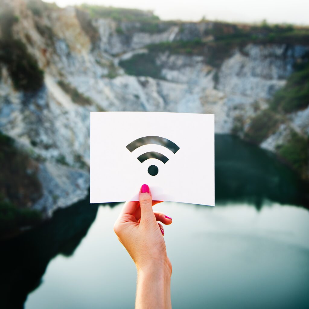 Mulher segurando um papel cortado no formato do um sinal de Wi-fi. Fundo de lago e montanhas. Pode ser entendido como estar conectado com a natureza e o universo.