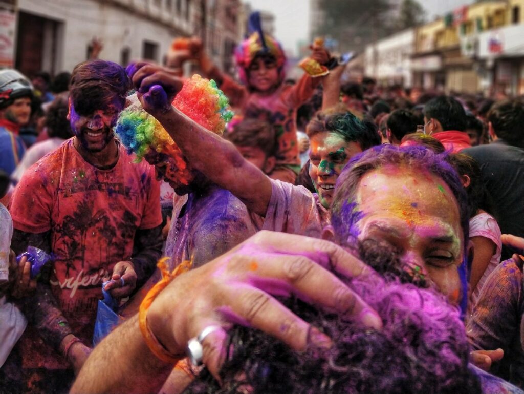 Folia na rua. Fumaça colorida e pessoas pintadas. Transmite sentimento de alegria.