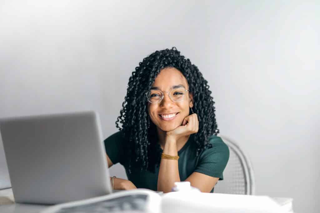 Mulher sorrindo em frente ao seu laptop.