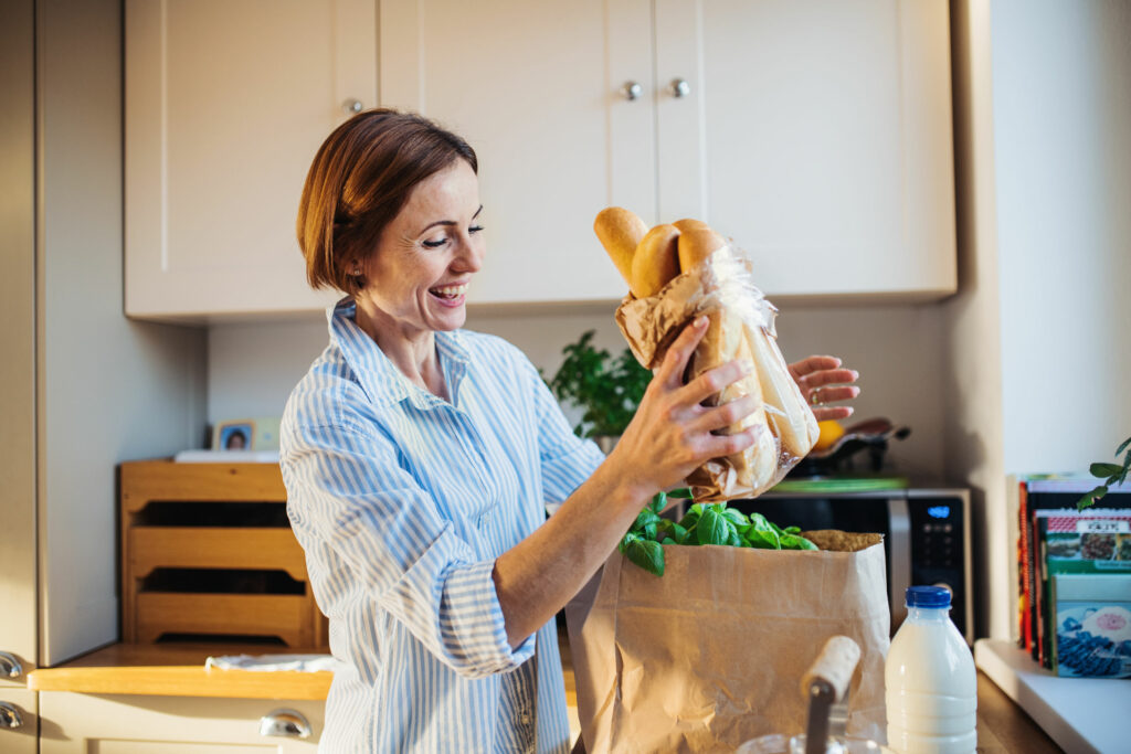 Uma jovem mulher chegando em casa com compras.