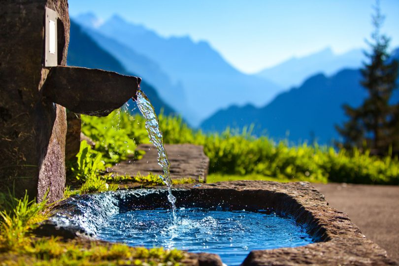 Fonte de água com paisagem de montanhas ao fundo.