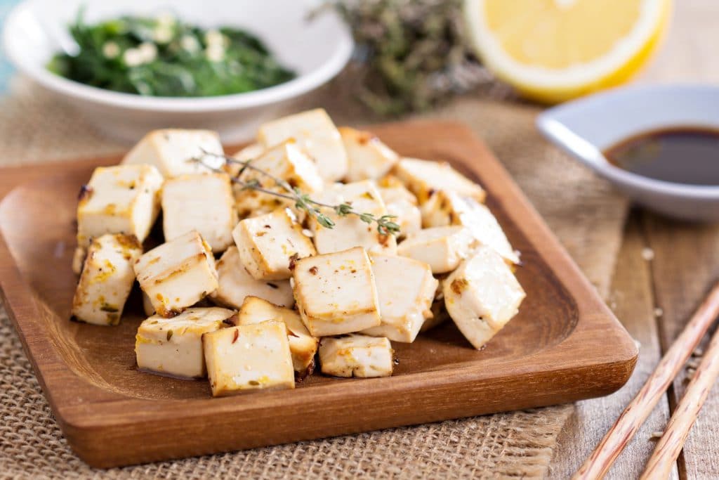 Tábua de madeira com diversos pedaços de tofu.