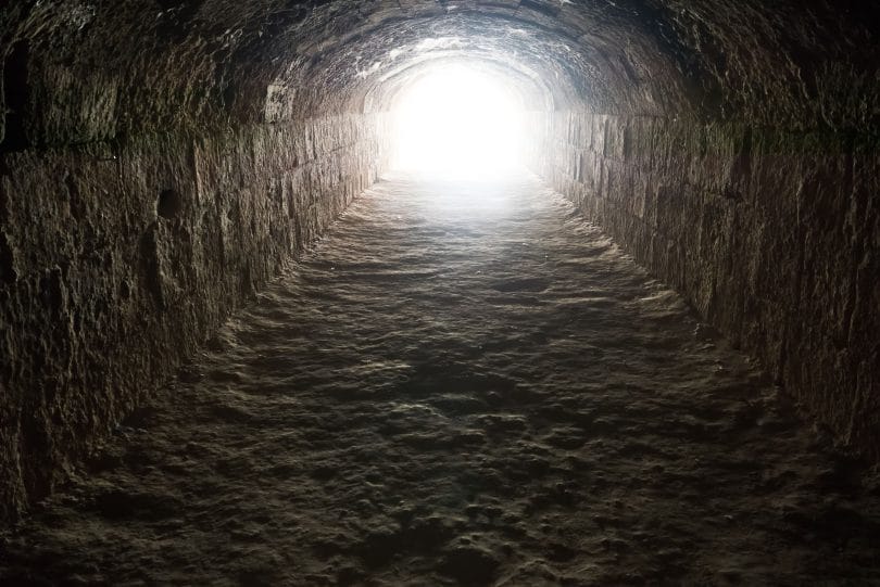Fundo de poço escuro, com uma luz brilhando na saída do topo.
