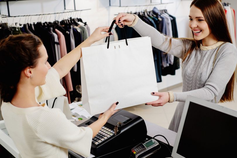 Consumidora comprando algo empacotado em sacola branca,