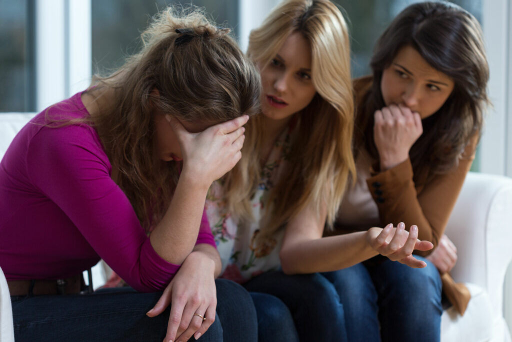 Menina chorando para as amigas enquanto elas aconselham.