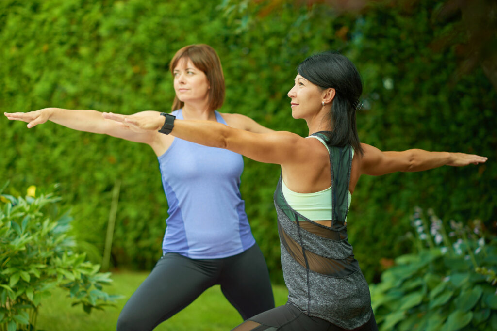 Duas mulheres, próximas aos 50 anos, praticando yoga