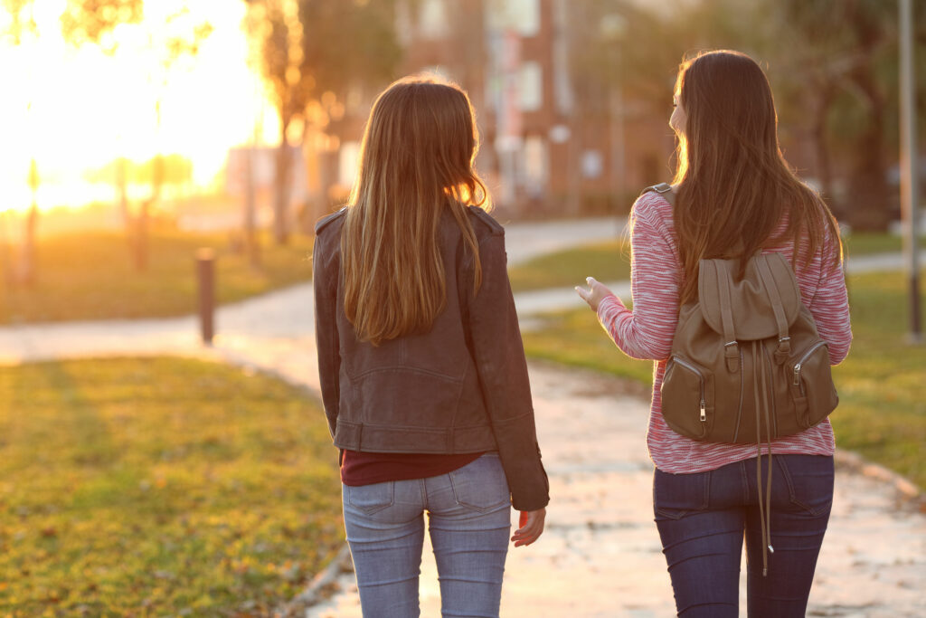 Amigas conversando enquanto andam em parque.