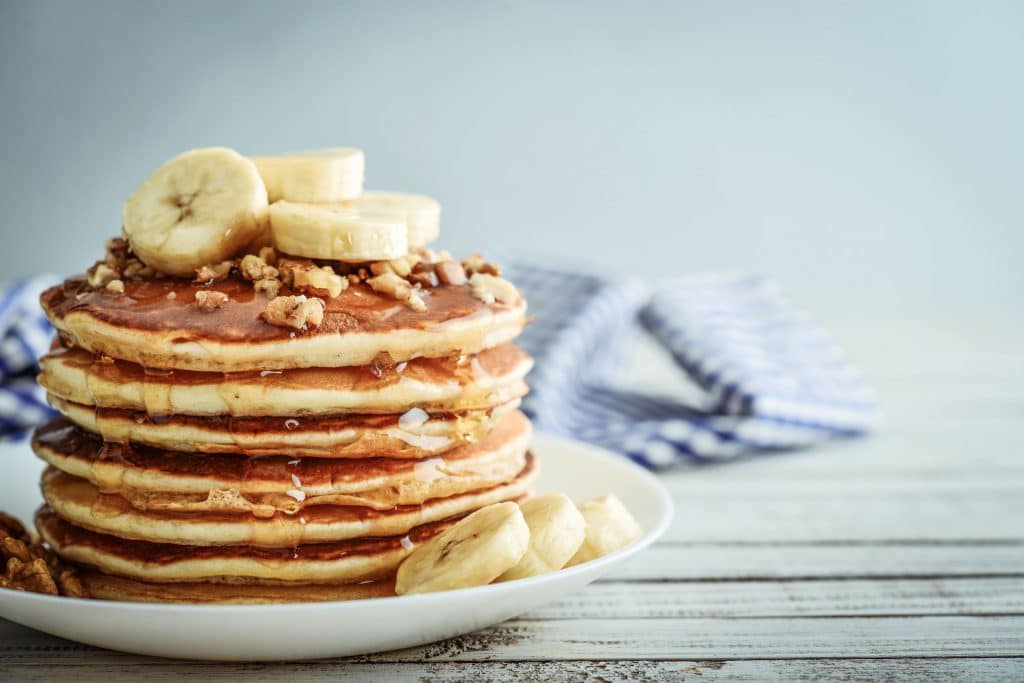 prato com panquecas americanas cobertas de melado e bananas fatiadas.