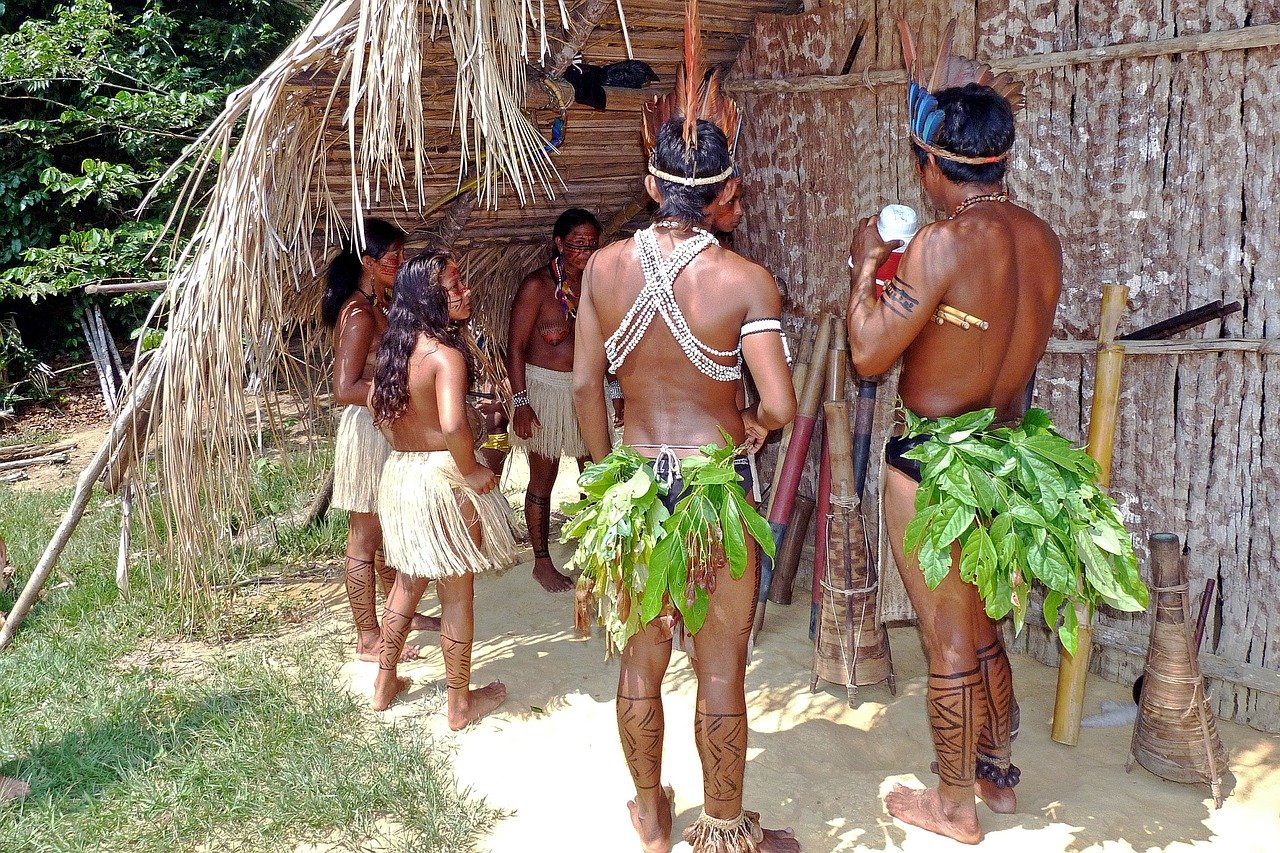 Grupo de índios na frente de uma oca. 