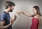 Homem e mulher discutindo. A mulher aponta o dedo para a cara do homem, enquanto este levanta os braços em sinal de irritação.