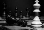 Peças de xadrez, uma rainha preta caída e um rei branca em pé