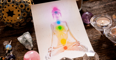 Ilustração em um papel de uma mulher com os sete chakras localizados em seu corpo. Ao lado, diversas pedras e cristais