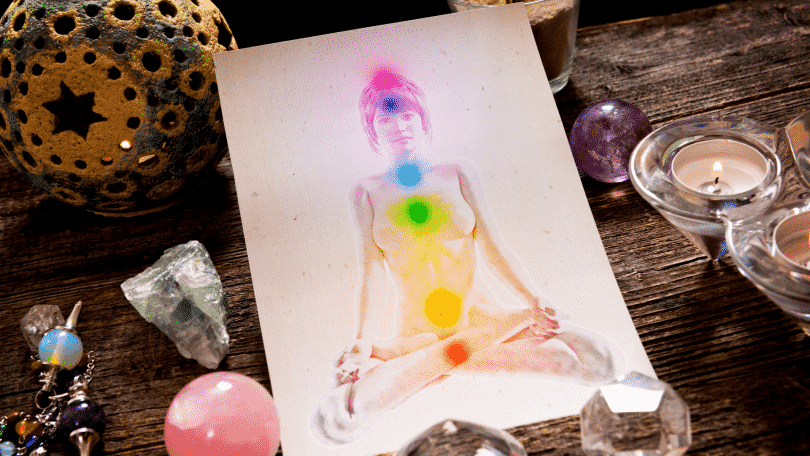 Ilustração em um papel de uma mulher com os sete chakras localizados em seu corpo. Ao lado, diversas pedras e cristais