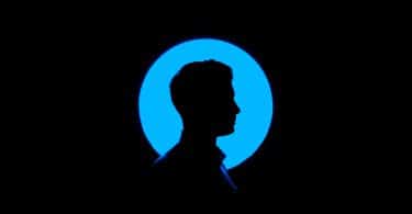 Silhuete de um homem de perfil em frente a uma fonte circular de luz azul sobre um fundo preto.