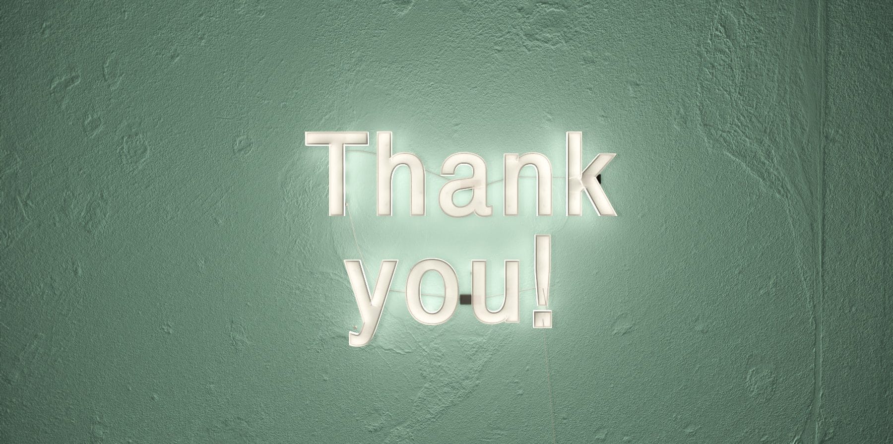 Letreiro escrito "Thank you" com luz de LED em uma parede verde.