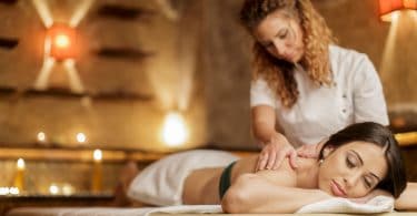 Terapeuta fazendo massagem em paciente deitada relaxada na maca