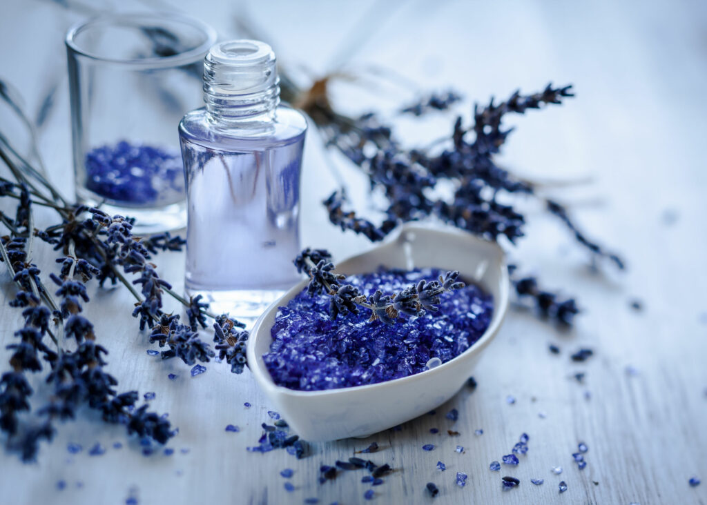 Óleo essencial de lavanda com algumas flores de lavanda em volta.