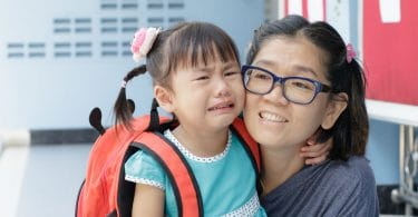 Mãe e filha no primeiro dia de escola, filha pequena chorando
