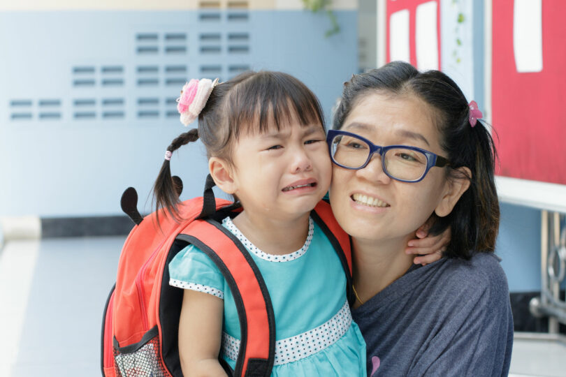 Mãe e filha no primeiro dia de escola, filha pequena chorando