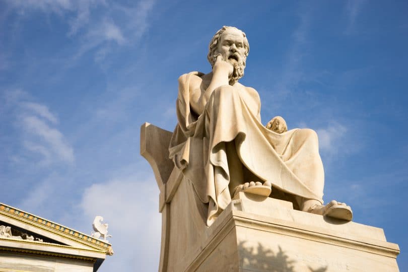 Escultura do filósofo Sócrates pensando sentado.