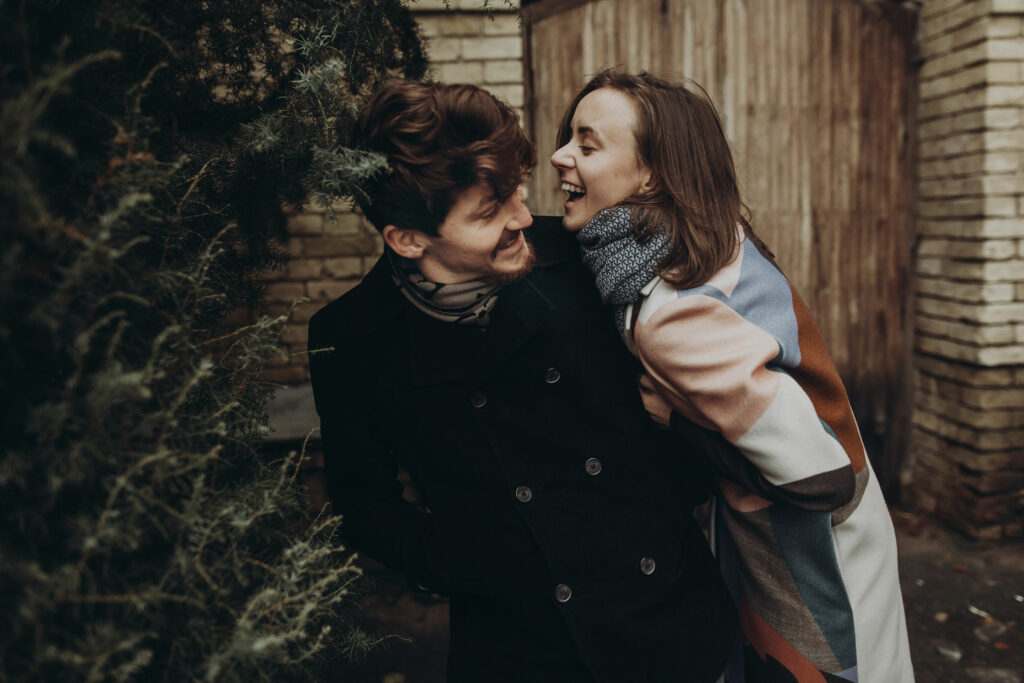 Casal jovem, rindo e sorrindo, se abraçando 