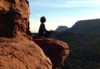 Mulher sentada sobre uma rocha em posição de meditação representando o eu sem fronteiras.