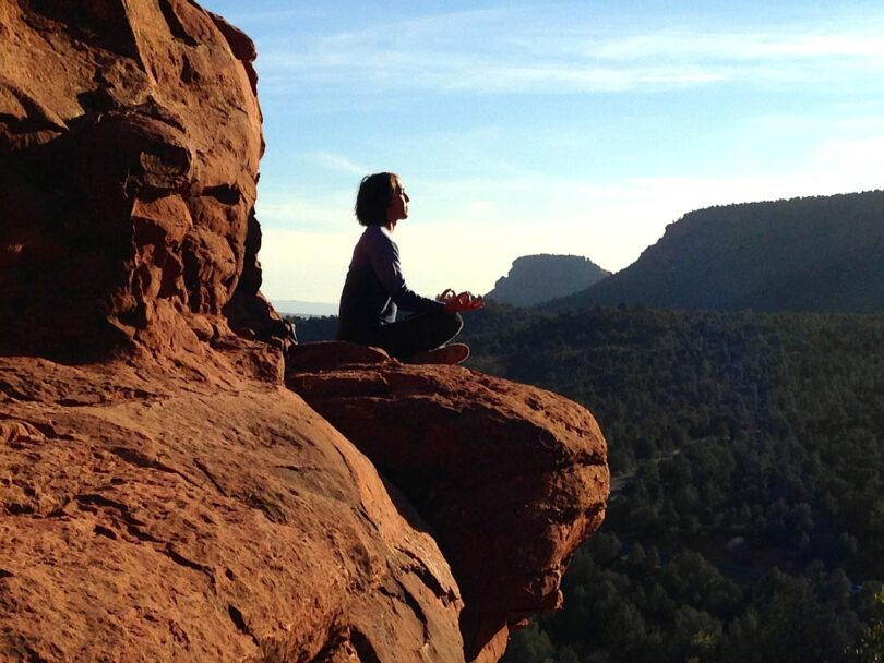 Mulher sentada sobre uma rocha em posição de meditação representando o eu sem fronteiras.