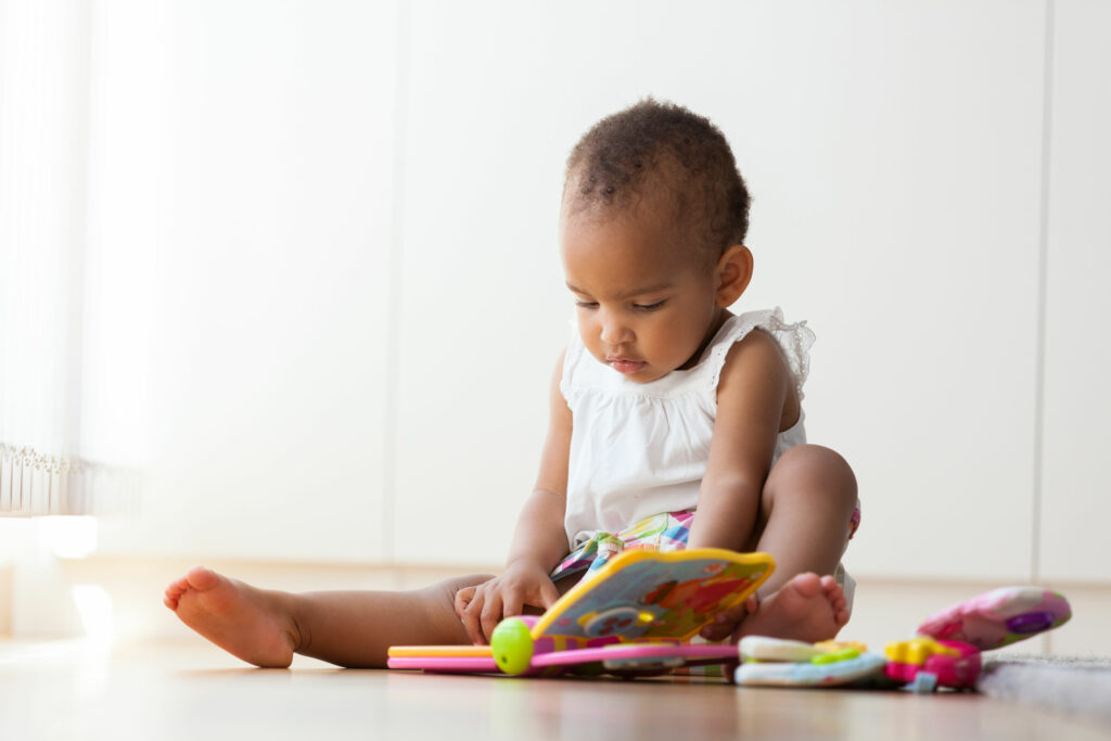 Bebê sentado no chão brincando com alguns brinquedos.