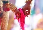 Mãos unidas por um pano rosa em um casamento hindu.