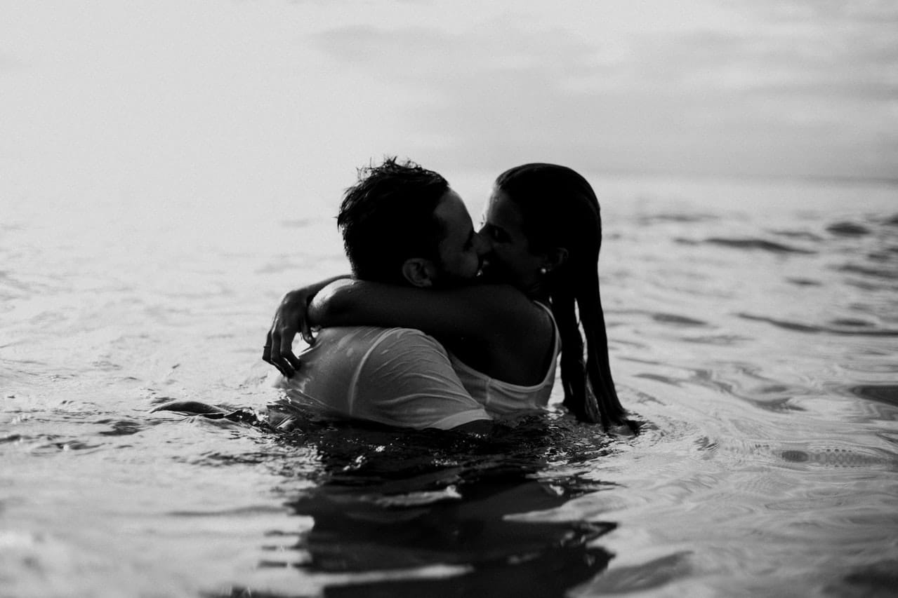 Casal na água abraçados se beijando em imagem preta e branca