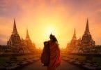 Monge caminhando entre templos em direção ao pôr-do-sol.