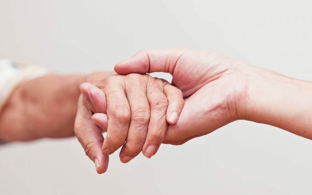 Mãos de duas pessoas brancas, uma pegando na outra