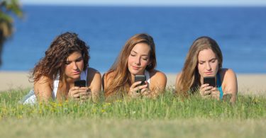 Três amigas mexendo no celular.