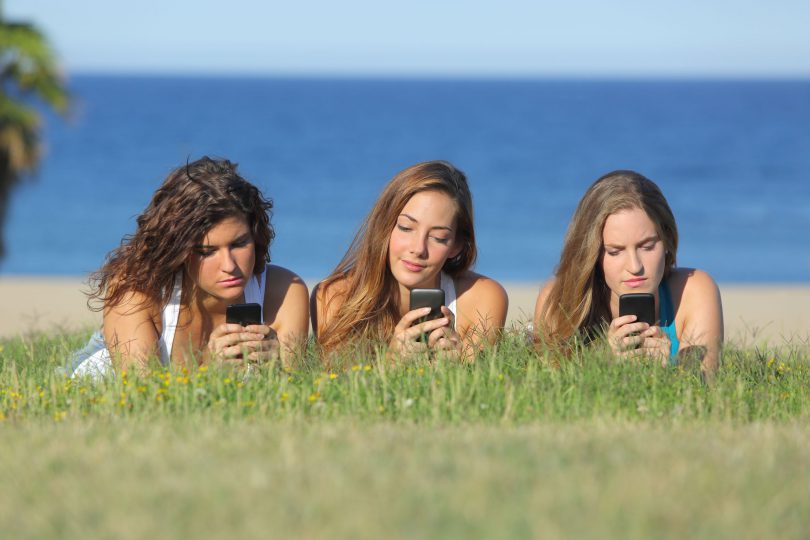 Três amigas mexendo no celular.