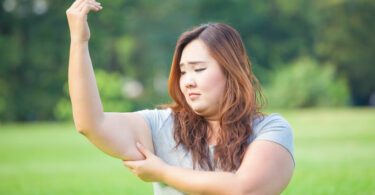 Mulher asiática apertando o braço