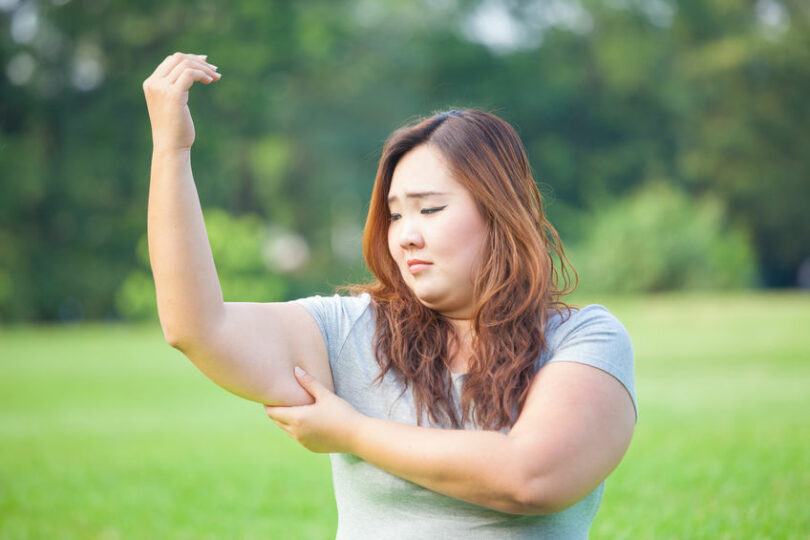 Mulher asiática apertando o braço