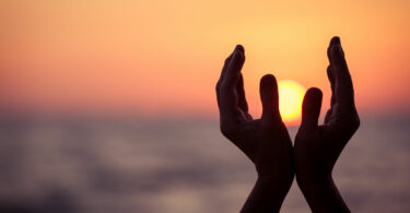 silhueta de mãos femininas durante o pôr do sol.