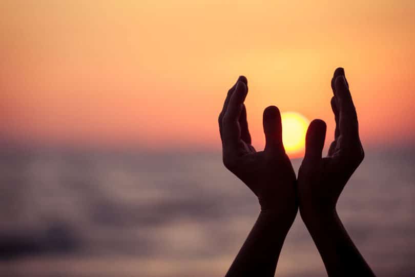 silhueta de mãos femininas durante o pôr do sol.