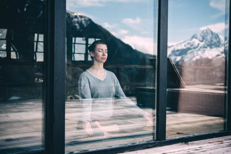Mulher meditando vista do lado de fora de vidro
