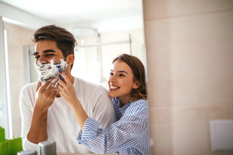 Casal brinca e dá risada enquanto o homem faz a barba.