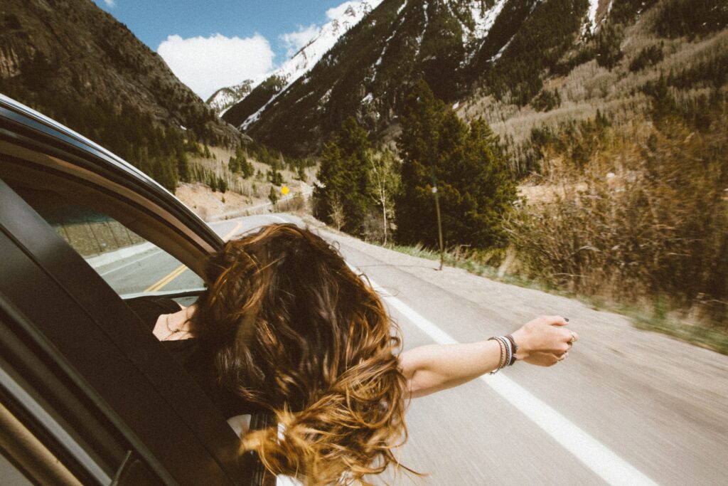 Mulher no carro com o cabelo voando.