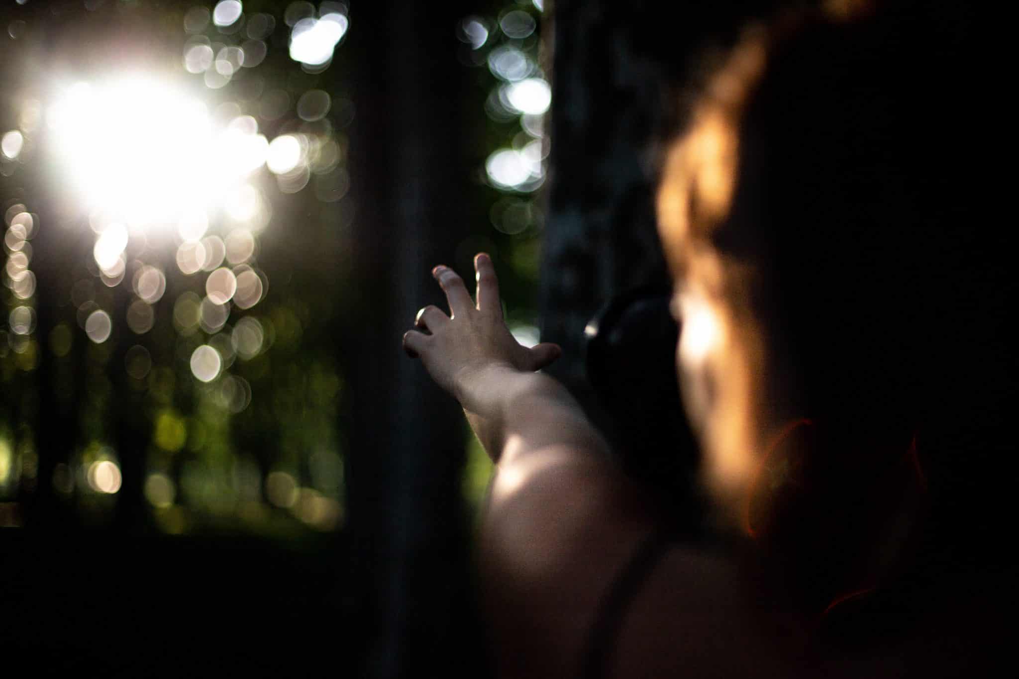 Mulher na floresta com o braço em direção ao sol