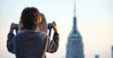 Menino de costas olhando para uma torre de fundo.