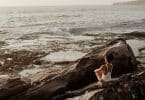 Mulher sentada em uma rocha olhando o mar