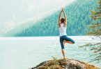 Mulher praticando yoga em frente a um ambiente marcado pela natureza.