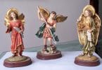Dia do Arcanjos: Estátuas dos Arcanjos Miguel, Gabriel e Rafael, todas em cima de uma mesa.